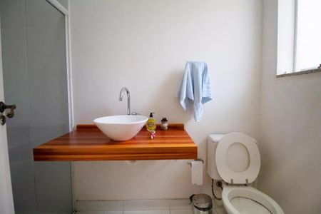 Casa à venda com 400m², 4 quartos e 6 vagasBanheiro com pia de madeira e vaso sanitário branco, com uma toalha azul pendurada na parede.