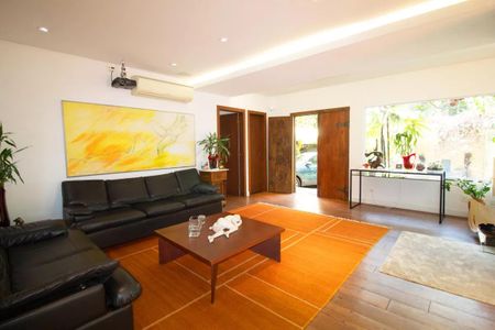Casa à venda com 400m², 4 quartos e 6 vagasSala de estar com móveis de couro e pintura de arte moderna, com vista para o jardim.