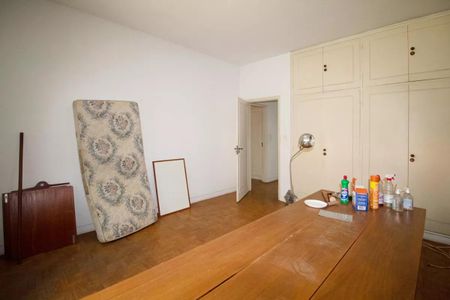 Casa à venda com 400m², 4 quartos e 6 vagasCama desmontada, porta de madeira e porta de vidro, parede branca e piso de madeira.