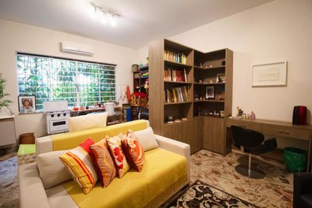 Casa à venda com 400m², 4 quartos e 6 vagasSala com sofá, mesa de trabalho e estantes de madeira, com vista para o jardim.