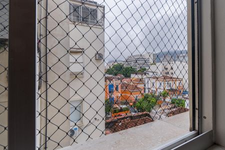 Apartamento à venda com 110m², 2 quartos e 1 vagaVista da cidade com edifícios e montanhas ao fundo, através de uma janela com grades de metal.