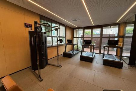 Apartamento à venda com 160m², 2 quartos e 3 vagasGinásio com equipamentos de treino e janelas grandes, iluminado com luz natural e artificial.