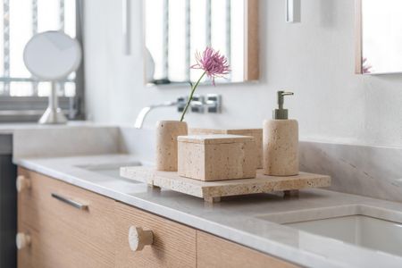 Apartamento à venda com 160m², 2 quartos e 3 vagasBanheiro com pia e vaso sanitário de pedra, com um vaso de flores na bancada.
