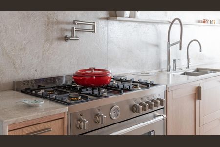 Apartamento à venda com 160m², 2 quartos e 3 vagasCozinha com fogão a gás e forno, pia e chafariz de água, e prato vermelho no fogão.
