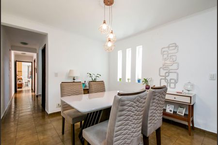 Casa à venda com 180m², 4 quartos e 2 vagasComedor com mesa branca e cadeiras de cor bege, iluminado por lâmpadas de design moderno.