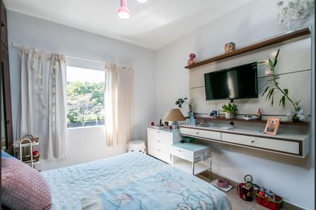 Casa à venda com 180m², 4 quartos e 2 vagasQuarto com cama, TV e móveis brancos, com vista para a rua e árvores.
