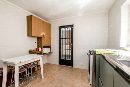 Casa à venda com 180m², 4 quartos e 2 vagasCozinha com móveis de madeira e piso de azulejos, com uma porta de vidro e uma janela pequena.