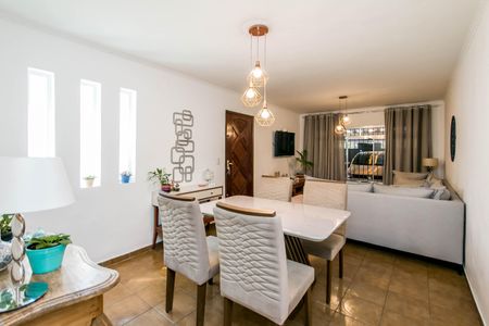 Casa à venda com 180m², 4 quartos e 2 vagasSala de jantar com mesa branca e cadeiras brancas, iluminada por lâmpadas de design, com vista para a rua.