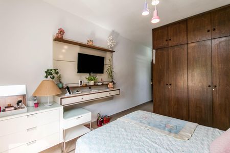 Casa à venda com 180m², 4 quartos e 2 vagasQuarto com cama, mesinha e TV, com móveis de madeira e plantas decorativas.