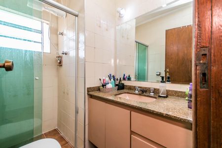 Casa à venda com 180m², 4 quartos e 2 vagasBanheiro com pia e chuveiro, com uma janela pequena e uma porta de madeira.