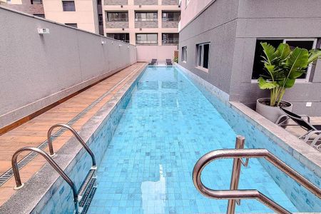 Apartamento à venda com 27m², 1 quarto e sem vagaPiscina com teto de vidro e paredes de concreto, cercada por uma parede de concreto e uma área de lazer com cadeiras e uma planta de bananeira.