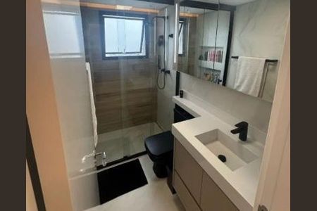 Apartamento à venda com 82m², 4 quartos e 2 vagasBanheiro com chuveiro, pia e vaso sanitário, com espelho e janela, em tons de cinza e branco.