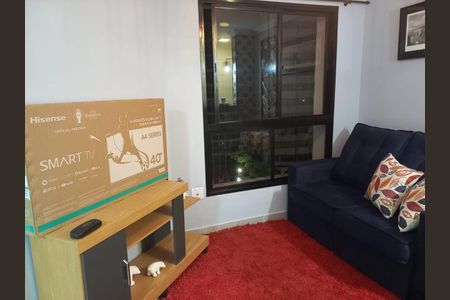 Apartamento à venda com 33m², 1 quarto e 1 vagaTV de 40 polegadas na sala de estar, com sofá azul e carpete vermelho.