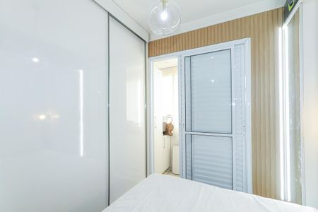 Apartamento à venda com 56m², 2 quartos e 1 vagaQuarto com cama, armários e iluminação adequada, com uma porta de vidro e uma janela pequena.
