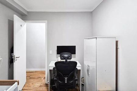 Apartamento à venda com 48m², 2 quartos e 1 vagaEscritório com mesa branca e cadeira preta, parede branca e piso de madeira.