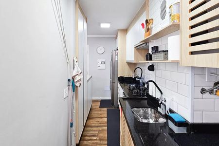 Apartamento à venda com 48m², 2 quartos e 1 vagaCozinha com geladeira, fogão e pia, com móveis de madeira e azulejos brancos.