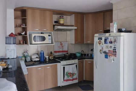 Cozinha com geladeira, fogão e microondas, com móveis de madeira e piso de porcelanato. de casa à venda com 4 quartos, 200m² em Jardim Santo Eduardo, Guarulhos