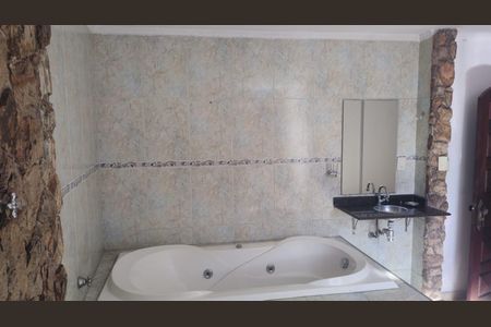 Banheiro com banheira de hidromassagem e pia duplo, com teto branco e paredes de azulejos e pedra. de casa à venda com 4 quartos, 200m² em Jardim Santo Eduardo, Guarulhos
