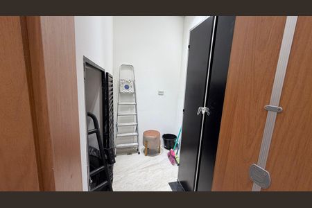 Parede branca com porta preta e escada de metal, com alguns objetos de limpeza no chão. de casa à venda com 2 quartos, 130m² em Vila Alzira, Santo André