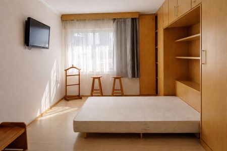 Apartamento à venda com 124m², 3 quartos e 2 vagasQuarto com cama, TV e móveis de madeira, iluminado por luz natural e artificial.