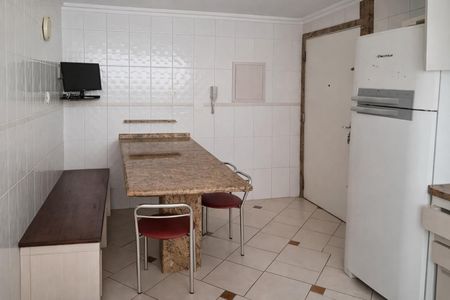 Apartamento à venda com 124m², 3 quartos e 2 vagasCozinha com mesa de granito, geladeira e TV montada na parede.
