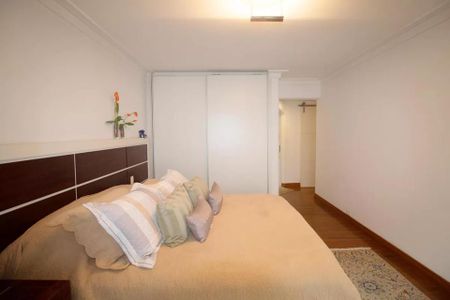 Apartamento à venda com 244m², 6 quartos e 3 vagas Apartamento à venda com 244m², 6 quartos e 3 vagasCama com colchão e travesseiros, com uma mesa de cabeceira e uma prateleira com flores.