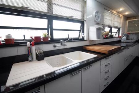 Apartamento à venda com 244m², 6 quartos e 3 vagas Apartamento à venda com 244m², 6 quartos e 3 vagasCozinha com pia dupla, bancada de granito e móveis brancos e prateados.