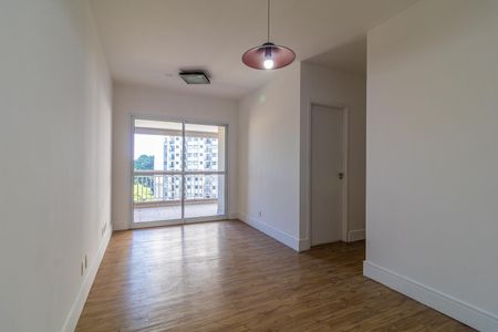 Apartamento à venda com 65m², 2 quartos e 1 vagaParede branca e piso de madeira, com vista para a varanda e o prédio ao fundo.