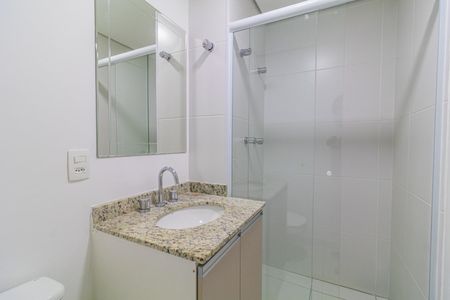 Apartamento à venda com 65m², 2 quartos e 1 vagaBanheiro com pia e vaso sanitário, com espelho e chuveiro, em ambiente branco e com azulejos brancos.
