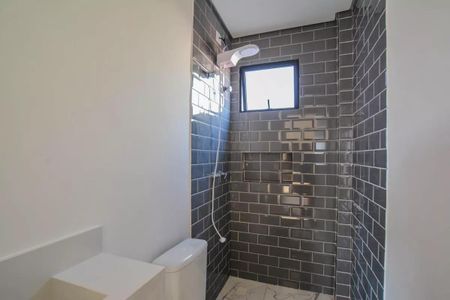 Apartamento à venda com 106m², 3 quartos e 1 vagaBanheiro com chuveiro e pia branca, paredes de azulejos pretos e piso de porcelanato branco.