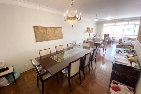Sala de jantar com mesa de madeira e cadeiras brancas, iluminada por uma lâmpada de cristal. de apartamento à venda com 4 quartos, 185m² em Jardim Paulista, São Paulo