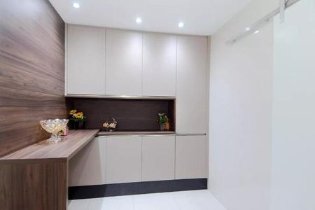 Apartamento à venda com 122m², 6 quartos e 2 vagas Apartamento à venda com 122m², 6 quartos e 2 vagasCabinets and countertop in a modern kitchen, with a bowl of fruit and a vase of flowers.