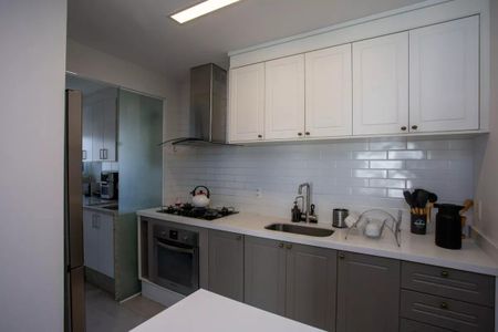 Apartamento à venda com 91m², 3 quartos e 2 vagas Apartamento à venda com 91m², 3 quartos e 2 vagasCozinha moderna com móveis brancos e cinza, iluminada por luzes brancas e com um fogão a gás e uma geladeira.