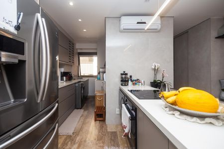 Apartamento à venda com 81m², 2 quartos e 2 vagasCozinha moderna com geladeira, fogão e pia, iluminada por luzes brancas e com móveis de madeira e azulejos brancos.