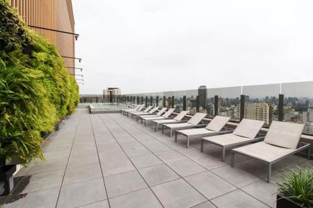 Studio à venda com 29m², 2 quartos e sem vagaVaranda com vista para a cidade, com cadeiras de praia e uma parede de plantas.