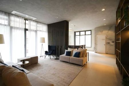 Studio à venda com 29m², 2 quartos e sem vagaSala com sofás, mesas e cadeiras, iluminada por lâmpadas e com vista para a janela.