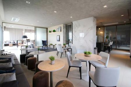 Sala de estar com sofás, mesas e cadeiras, iluminada por lâmpadas e com vista para a varanda. de kitnet/studio à venda com 2 quartos, 29m² em Itaim Bibi, São Paulo