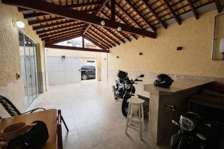 Casa à venda com 136m², 4 quartos e 2 vagas Casa à venda com 136m², 4 quartos e 2 vagasGaragem com piso de azulejo, teto de madeira e motocicletas estacionadas.