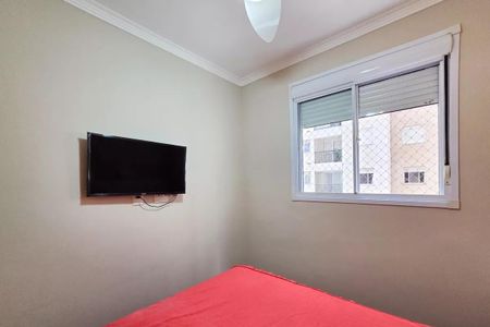 Apartamento à venda com 54m², 2 quartos e 1 vagaQuarto com cama vermelha e TV na parede, com vista para o prédio ao lado.