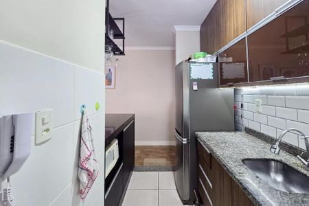 Apartamento à venda com 54m², 2 quartos e 1 vagaCozinha com geladeira, fogão e pia, com móveis de madeira e azulejos brancos.