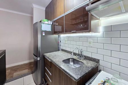 Apartamento à venda com 54m², 2 quartos e 1 vagaCozinha com geladeira, fogão e pia, com móveis de madeira e azulejos brancos.