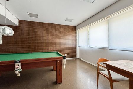 Apartamento à venda com 59m², 2 quartos e 1 vagaMesas de bilhar e mesa de jantar em uma sala com paredes de madeira e piso de porcelanato.