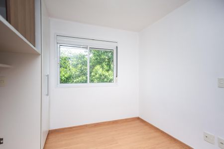 Apartamento à venda com 59m², 2 quartos e 1 vagaQuarto com janela e móveis brancos, com vista para a natureza.
