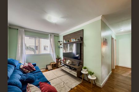 Sala de estar com sofá azul e TV montada na parede, com janela e porta para o exterior. de apartamento à venda com 3 quartos, 64m² em Paulicéia, São Bernardo do Campo