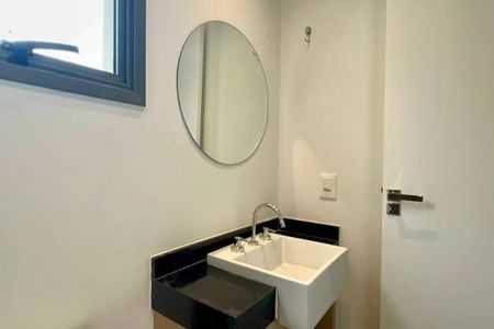 Apartamento à venda com 24m², 1 quarto e sem vagaBanheiro com pia branca e espelho redondo, com iluminação adequada e acabamento de gesso.