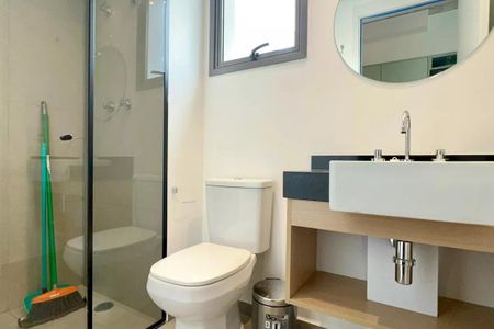 Apartamento à venda com 24m², 1 quarto e sem vagaBanheiro com chuveiro e vaso sanitário branco, pia e espelho em madeira, com varanda ao fundo.