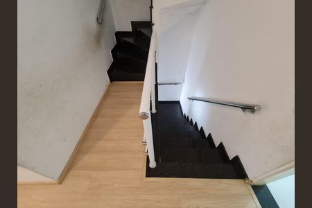 Casa à venda com 300m², 3 quartos e 3 vagasEscada interna de um prédio com pisos de madeira e azulejos, corrimão de metal e luz natural.