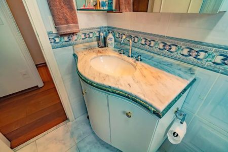 Apartamento à venda com 265m², 5 quartos e 3 vagasBanheiro com pia de mármore e azulejos azuis e brancos, com uma toalha pendurada no espelho.