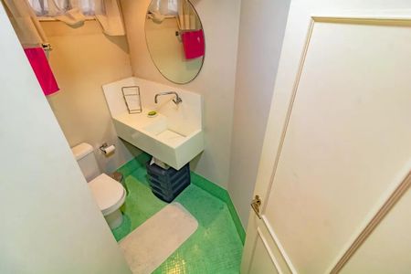 Apartamento à venda com 265m², 5 quartos e 3 vagasBanheiro com piso de azulejos, vaso sanitário e lavatório em formato de L, com espelho redondo e cortina de plástico.