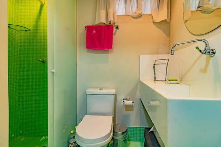 Apartamento à venda com 265m², 5 quartos e 3 vagasBanheiro com chuveiro e vaso sanitário branco, piso de azulejo verde e mosaico, com uma toalha vermelha pendurada no suporte de toalha, e uma janela com cortinas brancas.